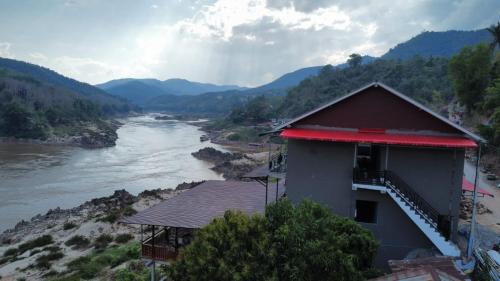 ein Gebäude neben einem Fluss mit Bergen im Hintergrund in der Unterkunft BOUAKHAI HOTEL Pakbeng in Pakbeng