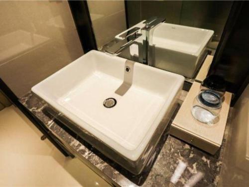 a white sink in a bathroom with a mirror at Echarm Hotel Jingjiang Bus Passenger Station Fanggu Street in Jingjiang