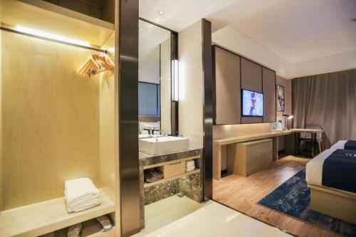 a bathroom with a bed and a sink and a mirror at Echarm Hotel Jingjiang Bus Passenger Station Fanggu Street in Jingjiang