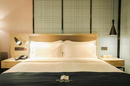 a bedroom with a large bed with white pillows at Echarm Hotel Jingjiang Bus Passenger Station Fanggu Street in Jingjiang