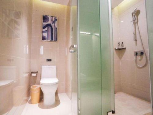 a bathroom with a toilet and a glass shower at Echarm Hotel Jingjiang Bus Passenger Station Fanggu Street in Jingjiang