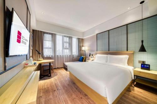 a bedroom with a large white bed and a flat screen tv at Echarm Hotel Jingjiang Bus Passenger Station Fanggu Street in Jingjiang
