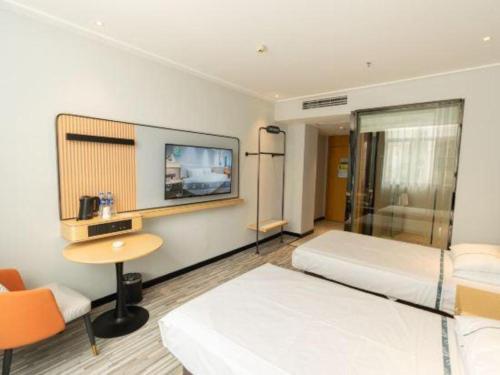 a room with two beds and a desk and a tv at City Comfort Inn Yingcheng Railway Station Shanghe Square in Xiaogan