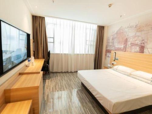 a hotel room with a large bed and a flat screen tv at City Comfort Inn Yingcheng Railway Station Shanghe Square in Xiaogan
