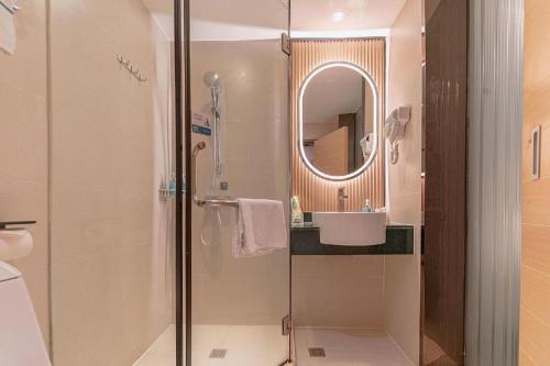 a bathroom with a shower and a sink and a mirror at City Comfort Inn Liuzhou High-speed Railway Station in Liuzhou