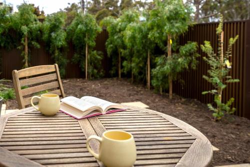 un tavolo con due tazze e un libro sopra di Torquay Haven Opposite Taylor Park 350m to Beach a Torquay