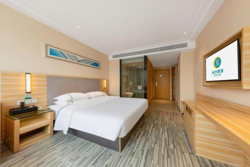 a hotel room with a bed and a flat screen tv at City Comfort Inn Zhanjiang South Zhenchuan Avenue in Zhanjiang