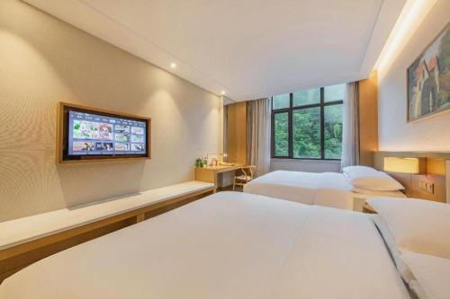 a bedroom with two beds and a flat screen tv at Deefly Yinrun Town Hotel in Deqing
