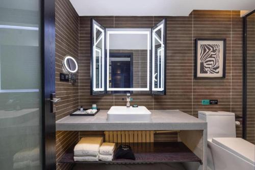 une salle de bain avec un lavabo et un miroir dans l'établissement Xana Hotelle Yining Airport Road Jinwuyuan, à Kipekyüzi