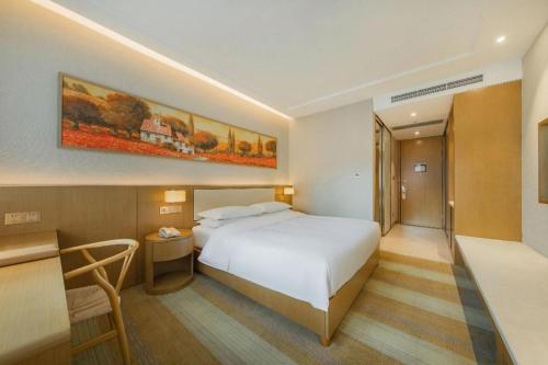 a bedroom with a large white bed and a desk at Deefly Yinrun Town Hotel in Deqing