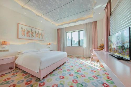 a bedroom with a large white bed and a desk at Deefly Yinrun Town Hotel in Deqing