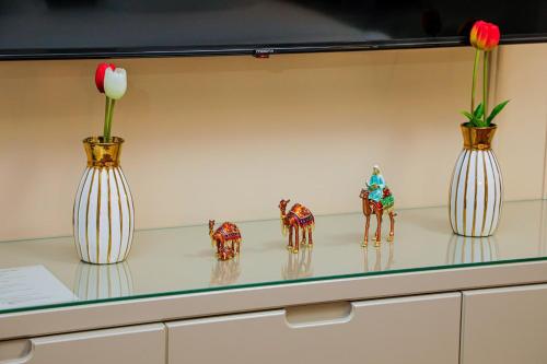 three vases and figurines on a shelf with flowers at Rakat Komfort Hotel Horizon Haven in Yakkasaray