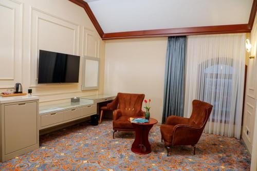 a hotel room with two chairs and a television at Rakat Komfort Hotel Horizon Haven in Yakkasaray