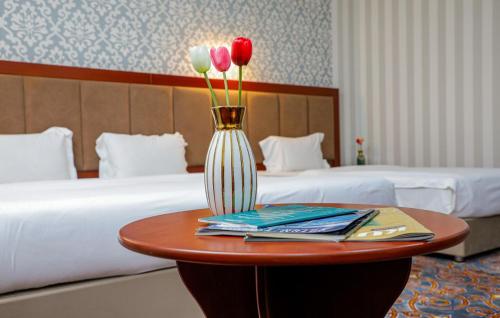 a table with a vase with three flowers on it at Rakat Komfort Hotel Horizon Haven in Yakkasaray
