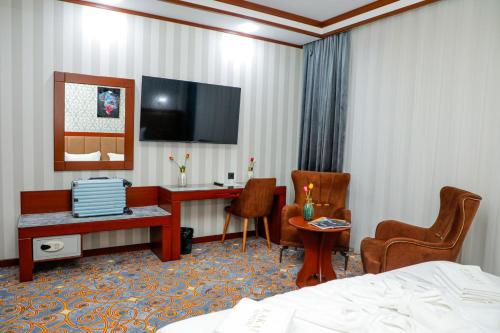 a hotel room with a bed and a desk and a tv at Rakat Komfort Hotel Horizon Haven in Yakkasaray