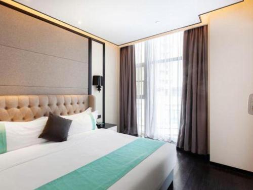 une chambre avec un grand lit et une grande fenêtre dans l'établissement Xana Hotelle Nanchang Xinhongcheng Grand Market Metro Station, à Taohua