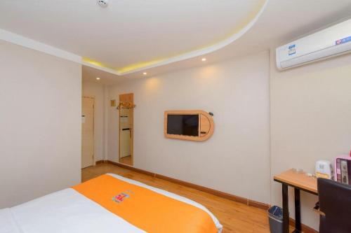 a bedroom with a bed and a tv on the wall at PAI Hotels Shijiazhuang Railway Station West Square in Shijiazhuang