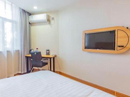 a hotel room with a bed and a tv on the wall at PAI Hotels Shijiazhuang Railway Station West Square in Shijiazhuang