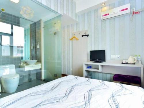 ein Schlafzimmer mit einem Bett und ein Badezimmer mit einem Waschbecken in der Unterkunft City 118 Hotel Qingdao Licang Pedestrian Street in Laoshan