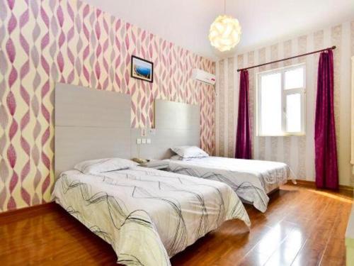 2 Betten in einem Zimmer mit rosa und weißer Tapete in der Unterkunft City 118 Hotel Qingdao Licang Pedestrian Street in Laoshan