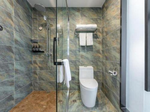 a bathroom with a toilet and a glass shower at Han Hotel Meisu Xi'an Longshouyuan Shenglong Plaza in Xi'an