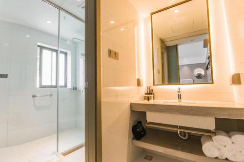 ein Badezimmer mit Dusche, Waschbecken und Spiegel in der Unterkunft Magnotel Hotel Huangshan Scenic Area Transfer Center in Huangshan Scenic Area