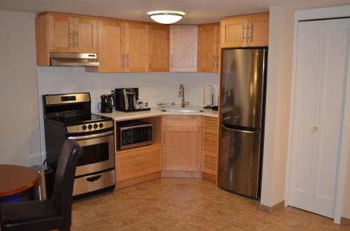a kitchen with wooden cabinets and a stainless steel refrigerator at Inn on Long Lake in Nanaimo