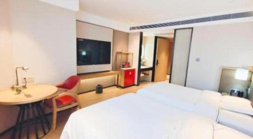 a bedroom with a bed and a desk and a table at E-Cheng Hotel Shenyang North Railway Station in Shenyang