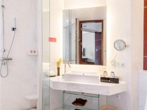 a white bathroom with a sink and a mirror at Balan International Hotel in Dujiangyan