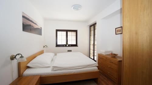 ein Schlafzimmer mit einem Bett, einer Kommode und einem Fenster in der Unterkunft Vila Olympia - Apartmán Olympia 3 in Ružomberok