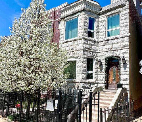 a stone house with a fence and a tree at The Banksy-Free Parking -4 bedroom w King bed- Firepit Rooftop near United Center in Chicago