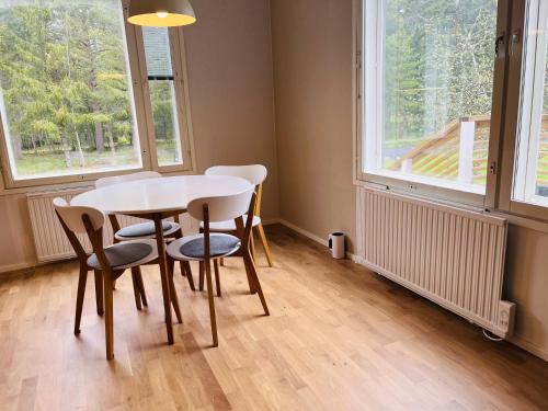 a table and chairs in a room with windows at Villa Kuninkaankivi in Kalajoki