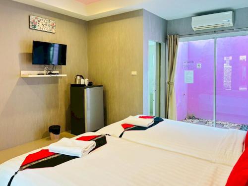 a hotel room with two beds and a tv at Baan Phing Phu Praew Cha-Am Resort บ้านพิงภูแพรว รีสอร์ท ชะอำ in Cha Am