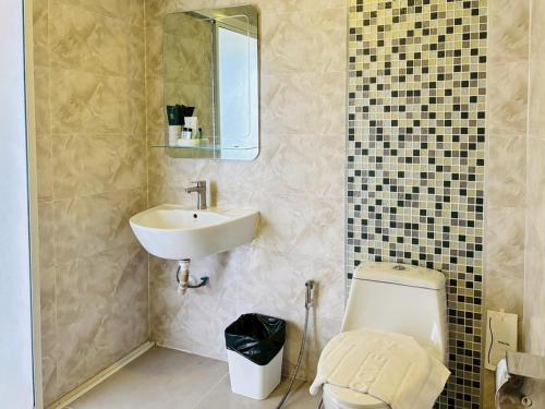 a bathroom with a sink and a toilet and a mirror at Baan Phing Phu Praew Cha-Am Resort บ้านพิงภูแพรว รีสอร์ท ชะอำ in Cha Am