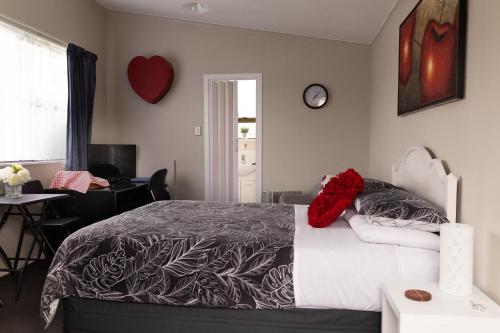 a bedroom with a bed with red pillows on it at Quiet Boutique Generous Breakfast in Palmerston North