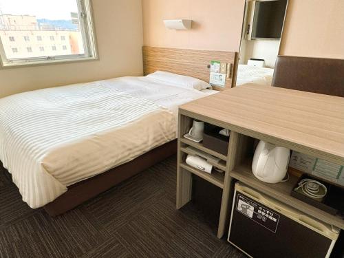 a hotel room with a bed and a table at Super Hotel Hirosaki in Hirosaki
