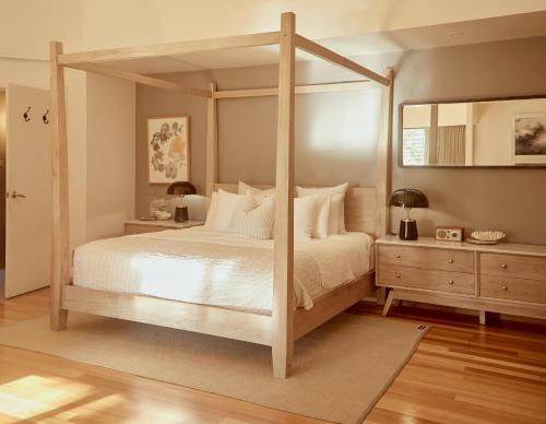 a bedroom with a wooden canopy bed with white pillows at Empire Spa Retreat in Dunsborough