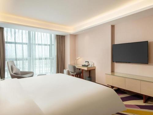 a hotel room with a bed and a flat screen tv at Lavande Hotel Zhongshan Xiaolan Taifeng in Jilong