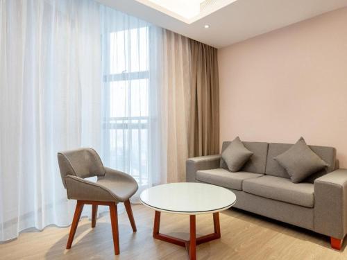 a living room with a couch and a table and a chair at Lavande Hotel Zhongshan Xiaolan Taifeng in Jilong