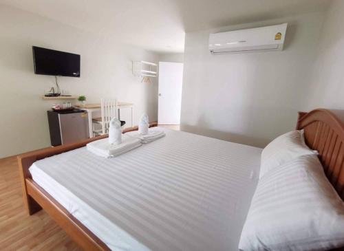 a large white bed in a room with a tv at Lert Sri Hotel in U Thong