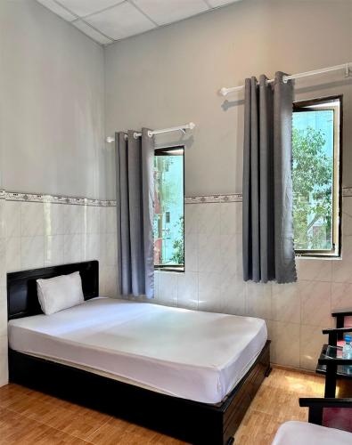a bed in a room with two windows at Nam Đô Hotel Cần Thơ Downtown in Can Tho