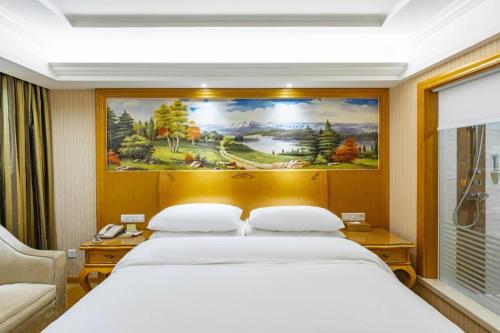 une chambre avec un grand lit avec un tableau au mur dans l'établissement Vienna Hotel Hunan Hengyang Leiyang, à Leiyang