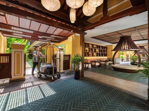 a man standing in a lobby with a luggage cart at The Signature Hoi An in Hoi An
