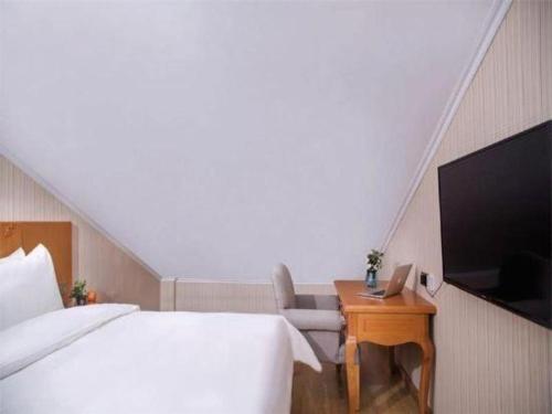 a bedroom with a bed and a desk with a tv at Vienna Hotel Inner Mongolia Tongliao Development Zone in Tongliao