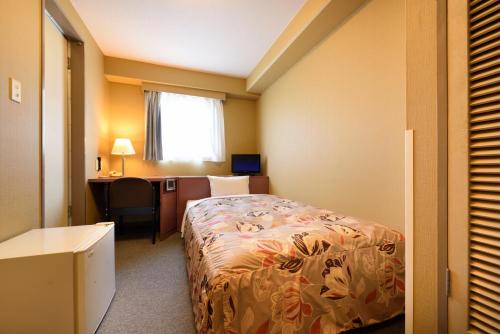 a hotel room with a bed and a desk with a computer at Hotel Park Sendai 2 in Sendai