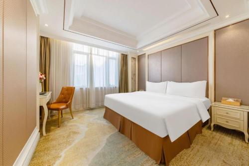 a hotel room with a large bed and a chair at Vienna Hotel Guangdong Shantou South Bus Station in Shantou