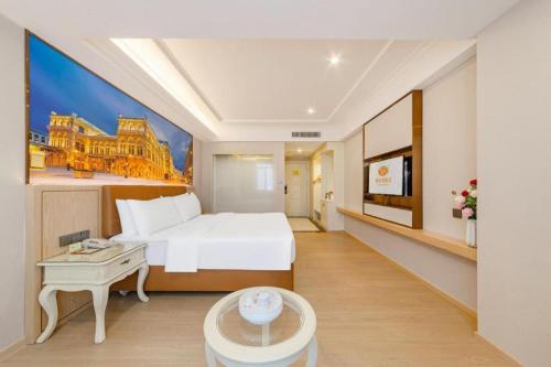 a hotel room with a white bed and a table at Vienna Hotel Guangdong Shantou South Bus Station in Shantou