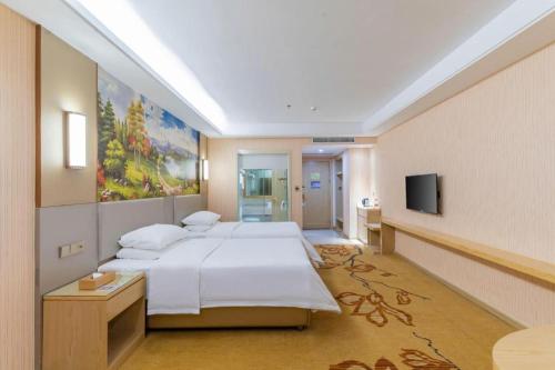 pokój hotelowy z łóżkiem i telewizorem w obiekcie Vienna Hotel Guangdong Huizhou High-Speed North Railway Station Xiaojinkou w mieście Huizhou
