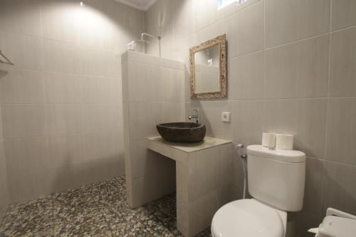 a bathroom with a white toilet and a sink at KT. Kuaya Home Stay in Ubud