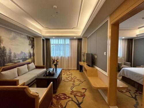 a hotel room with a couch and a bed at Vienna Hotel Guangdong Huiyang Qiuchang Yingbin Road in Huizhou